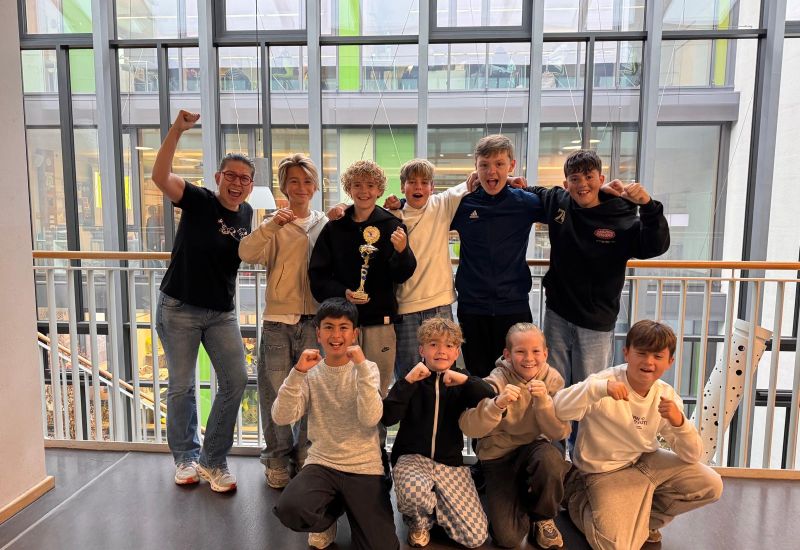 Schulleiterin Frau Amrhein und die erfolgreichen Schüler der Comenius-Realschule jubeln mit dem Siegerpokal für den 3. Platz beim Junior Messe-Cup.
